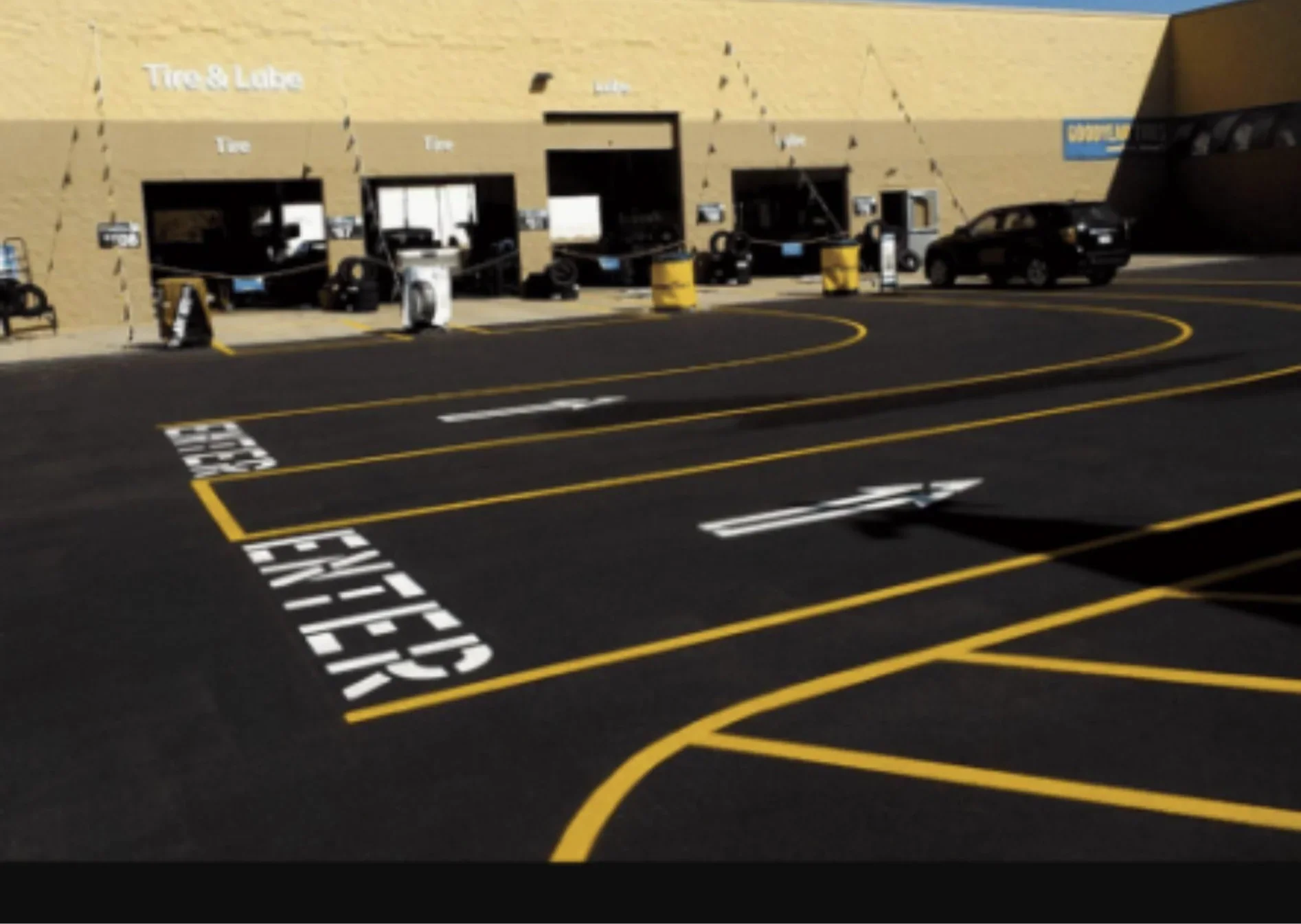 Paving crew from a commercial paving company repairing potholes and cracks in a busy parking lot for safety and liability protection.